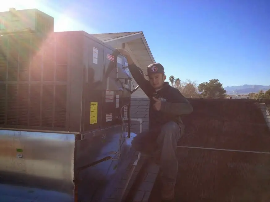 HVAC technician performing AC Tune-Up on a rooftop unit in Elwood